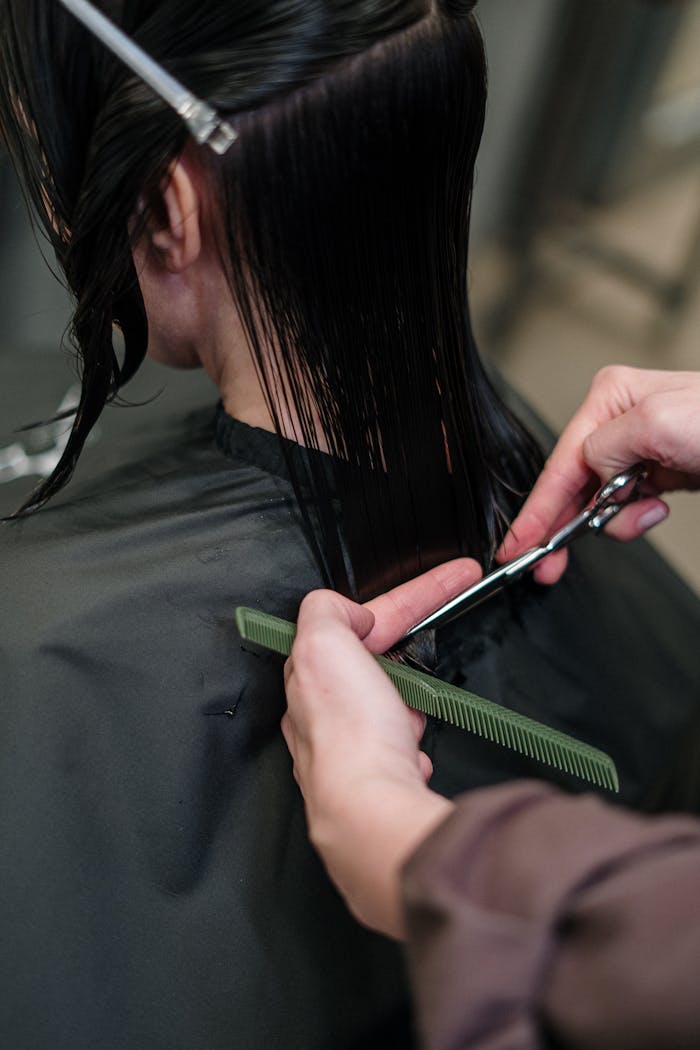 Close-up of a hairstylist cutting a woman's hair in a salon, showcasing precise techniques.