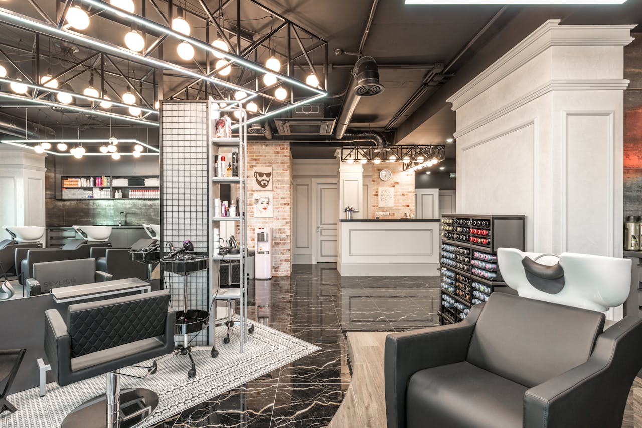 Backwash chair with sink placed near shelves with cosmetology products and reception desk in stylish beauty salon with decorated walls