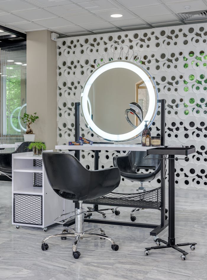 Chic salon setup featuring sleek chairs and illuminated vanity mirror.