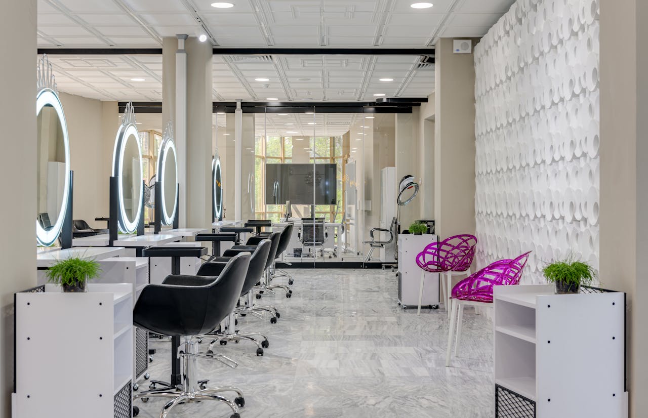 Contemporary salon interior featuring sleek chairs and illuminated vanity mirrors.